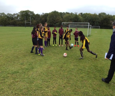 Students in football kit on the sports field